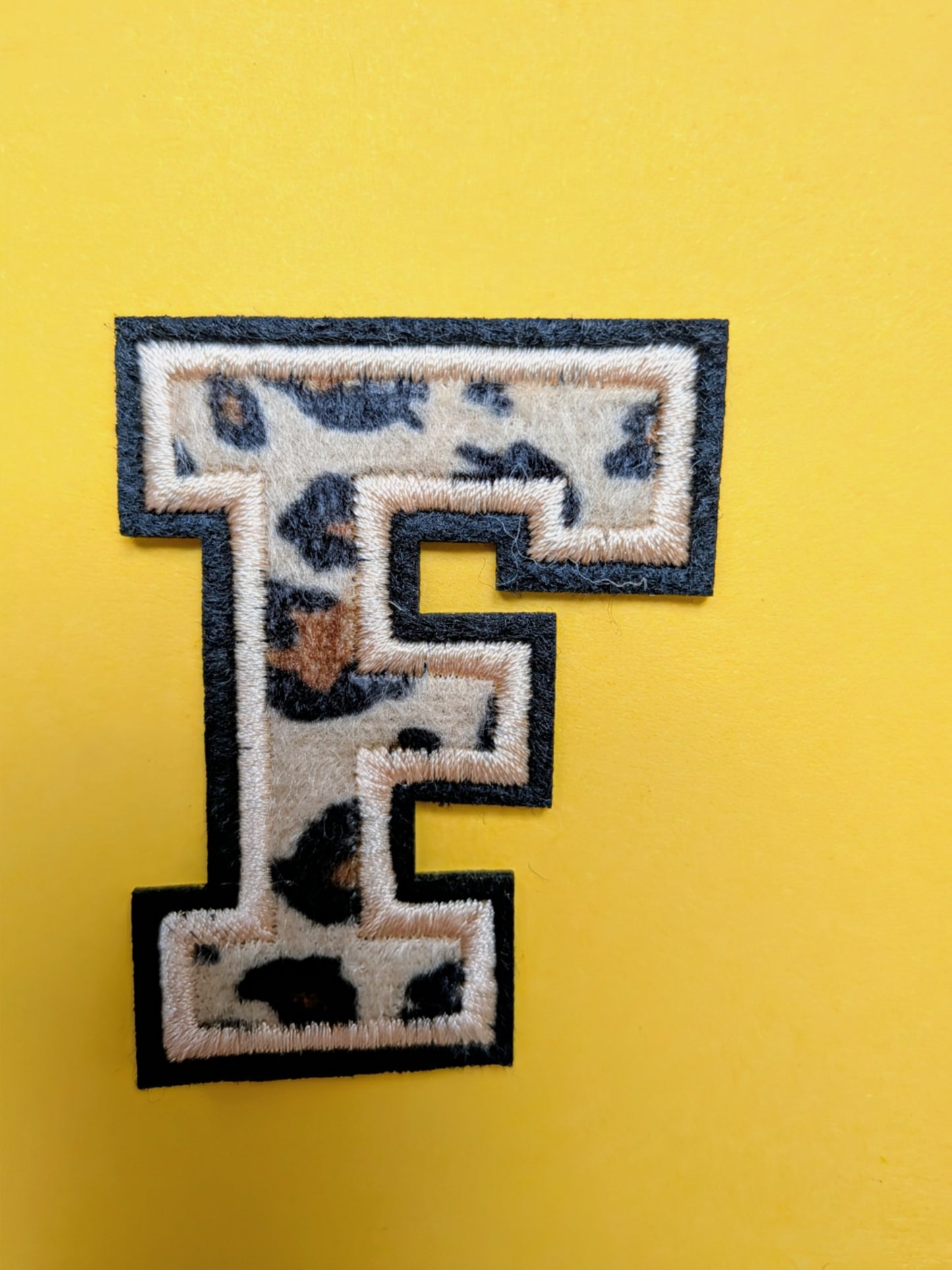 Close-up van stoffen animal print op college letter patch β T is for Teddie